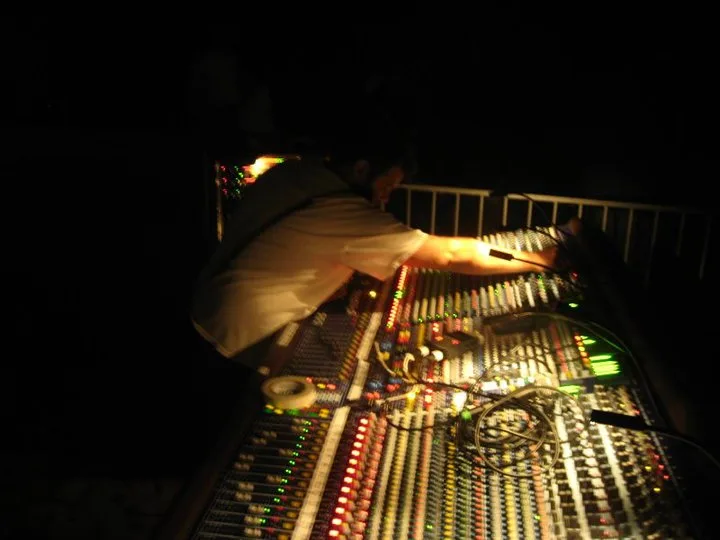 Casey leaning over a large analog mixing console in a dark venue